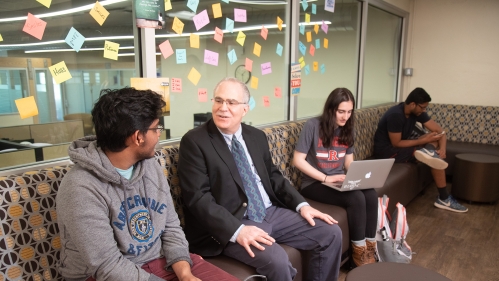 An advisors taking to a student, with 2 students in the background..