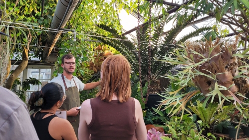 A greenhouse manager and two students in a greenhouse.