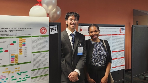 A student and an adult standing next to a research poster.