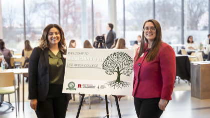 Two administrators standing next to a sign that reads, 'Welcome to Branching Out! Life After College'.