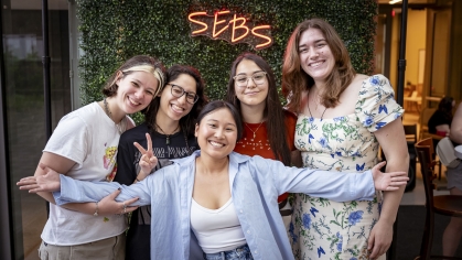 Five students in front of a 'SEBS' sign.