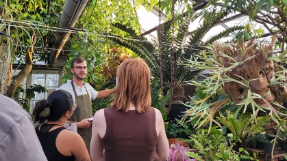 A greenhouse manager and two students in a greenhouse.