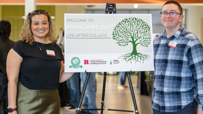 Two people posing next to a sign about the Branching Out event