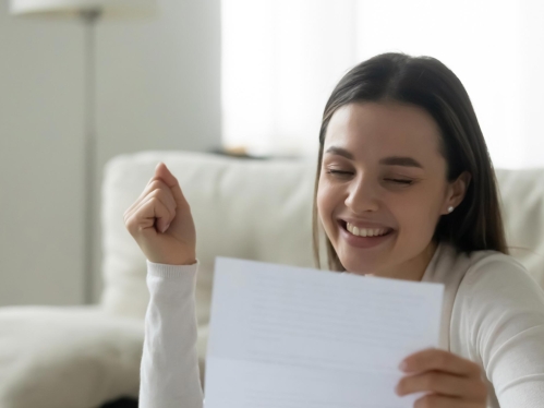 A student looking at a letter and smiling.