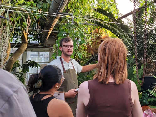 A greenhouse manager and two students in a greenhouse.