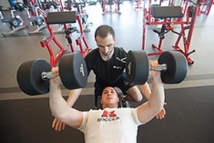 A trainer spotting a student lifting weights.